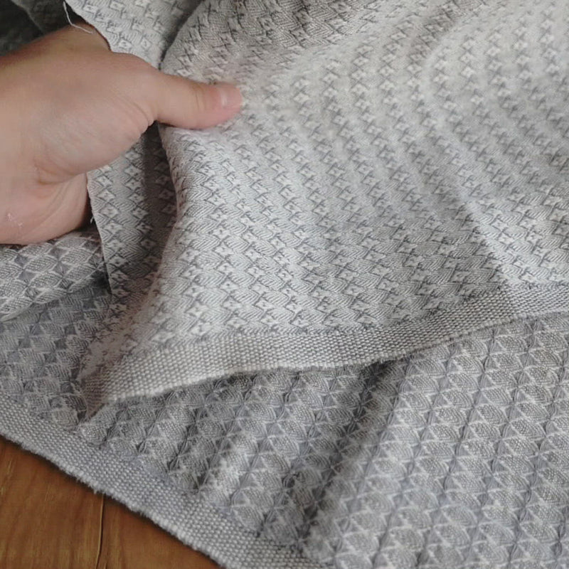 A grey and white fabric woven in a honeycomb pattern. 