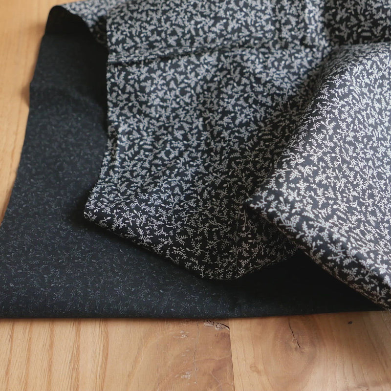 Black fabric printed with a white, tiny leaf pattern.
