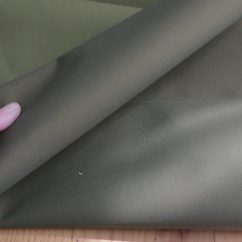 Hand crumples stiff green fabric.