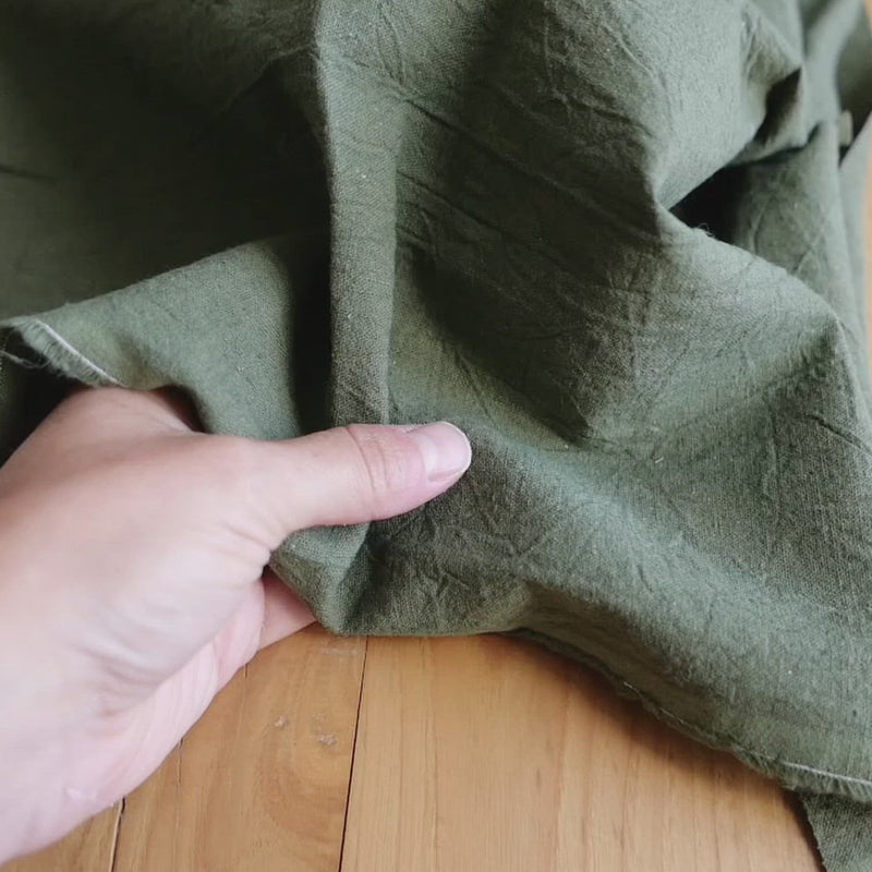 Plain green fabric with a creased texture. 