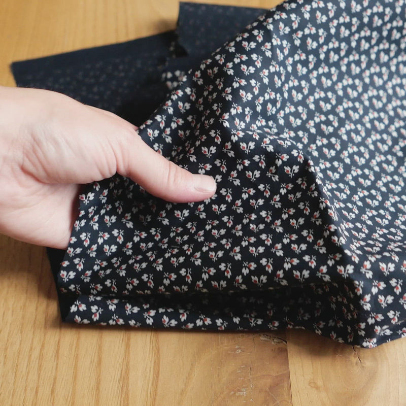Navy fabric printed with a tiny white & red leaf pattern.