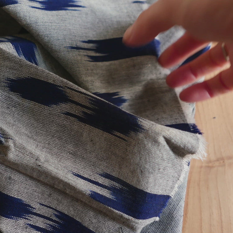 Black and white chambray fabric with a blue woven geometric pattern. 