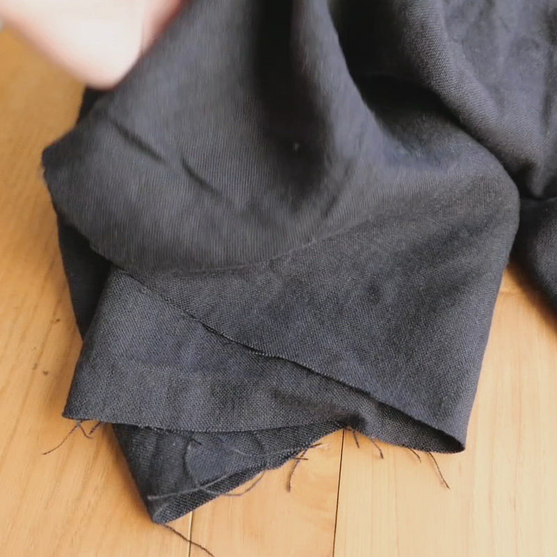 Hand crumples navy linen with a brushed texture.
