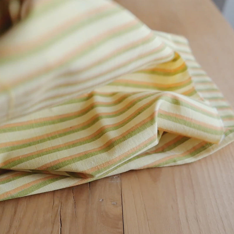 Yellow fabric with green and orange stripes. 