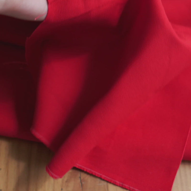 Hand crumples stiff red canvas.