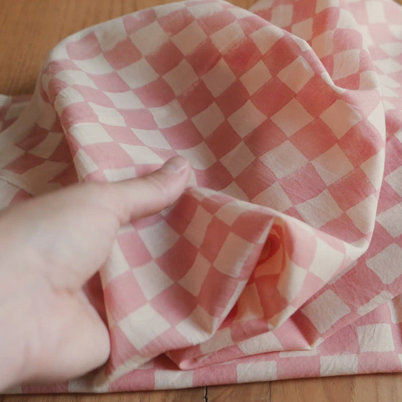 Hand crumples cotton with check pattern.