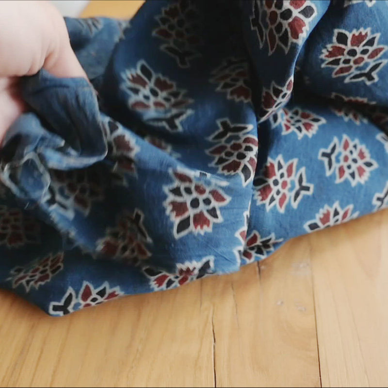 Hand crumples indigo cotton with red and black flowers.