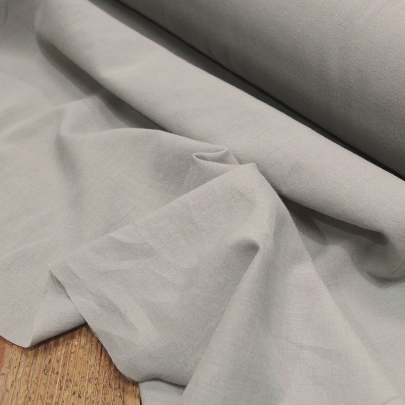 Hand crumples fine, grey cotton fabric.