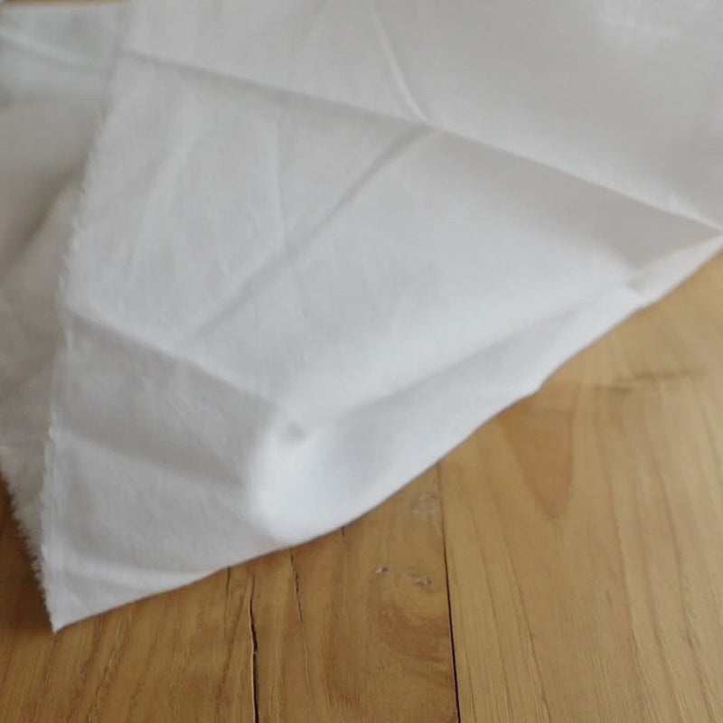 Hand crumples sheer white cotton fabric.