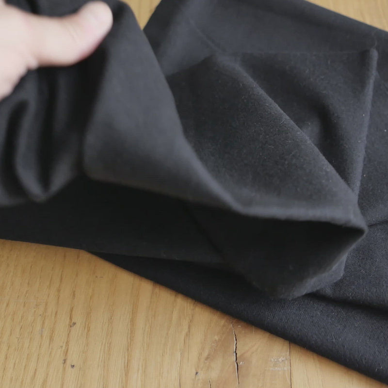 Hand crumples brushed cotton in black.