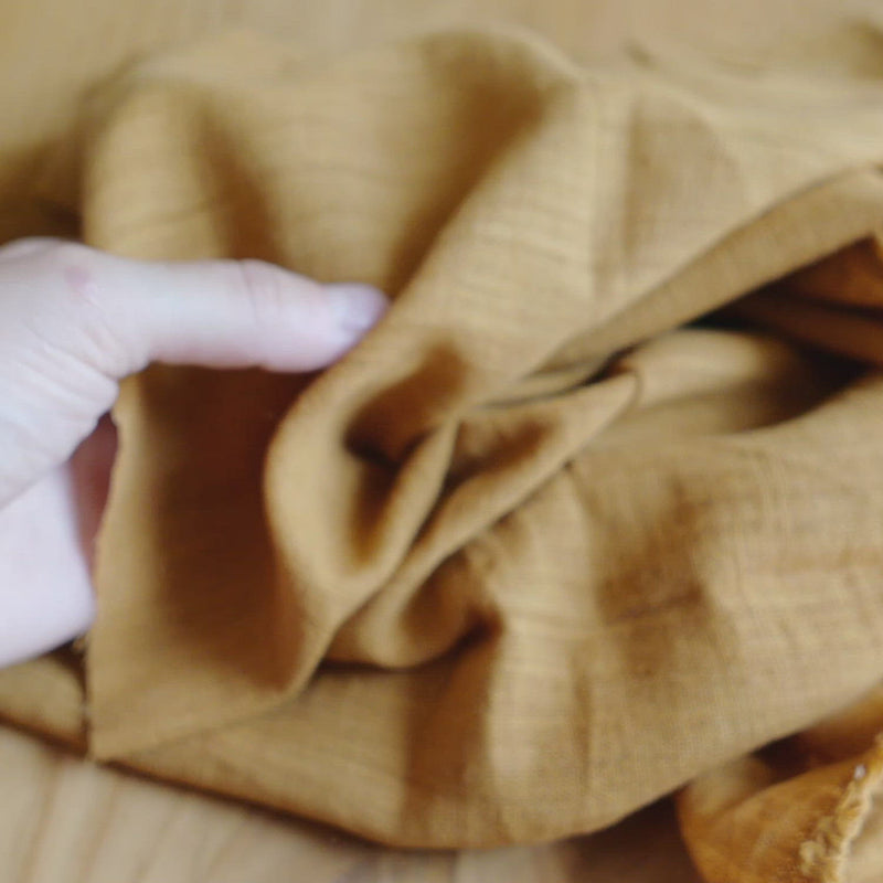 Ochre coloured fabric, with a slubby texture.