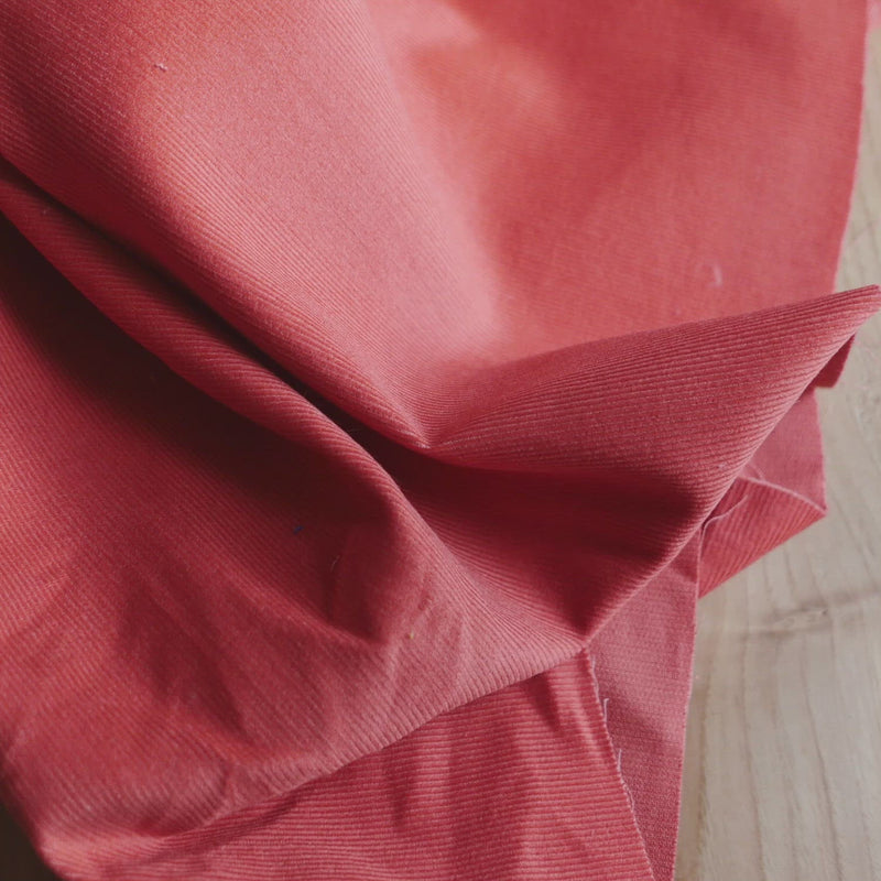 Orange corduroy fabric with a very fine cord.