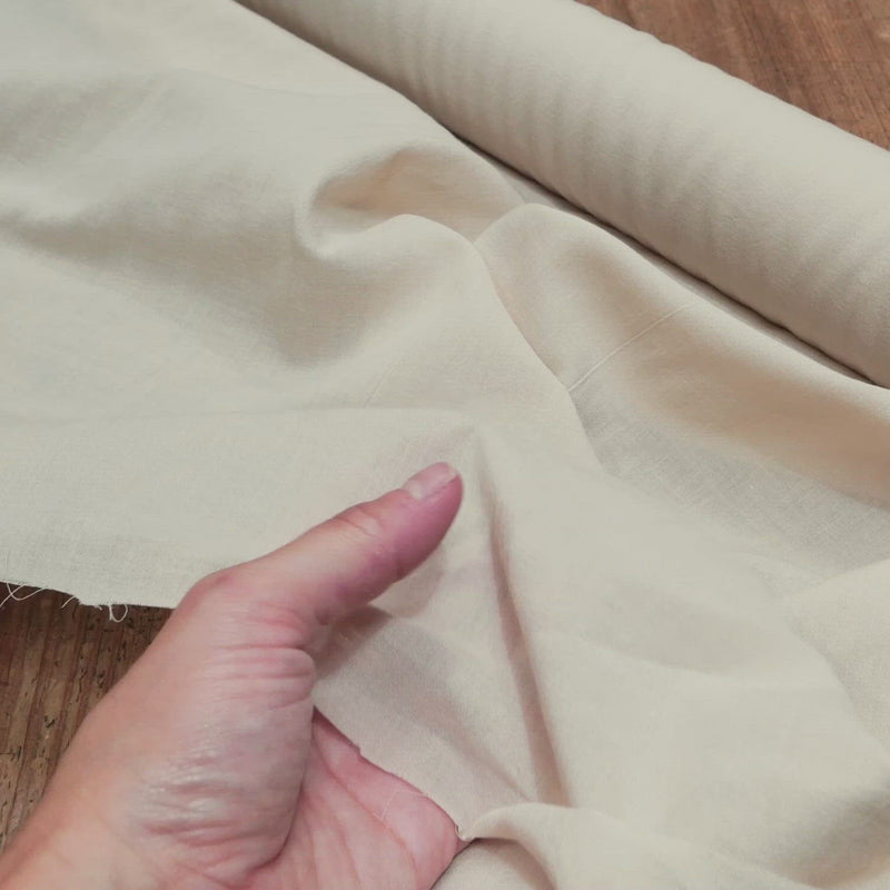 Hand crumples sand coloured cotton fabric.
