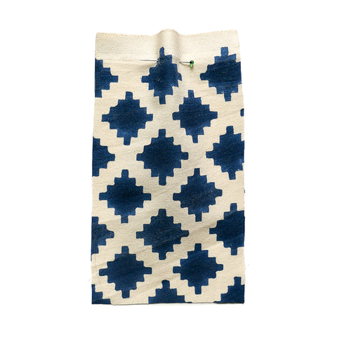 Cream cotton fabric with a blue printed geometric pattern..