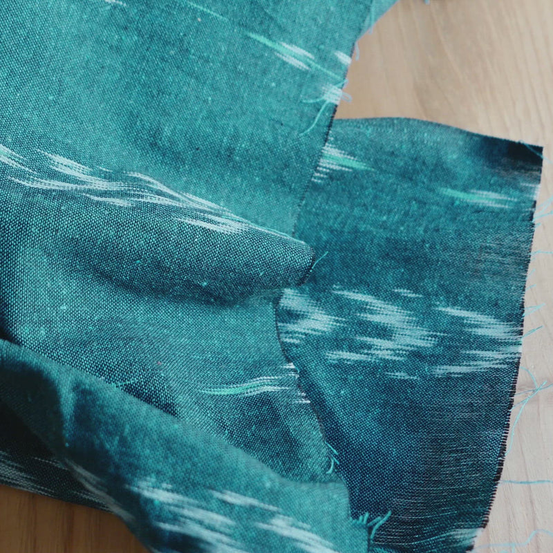 Teal fabric woven with a light blue geometric shape.
