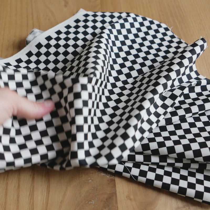 Hand crumples black and white checkerboard fabric.