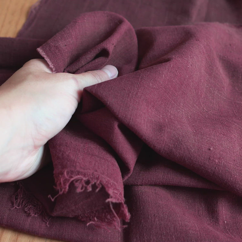 Burgundy coloured fabric, with a slubby texture.
