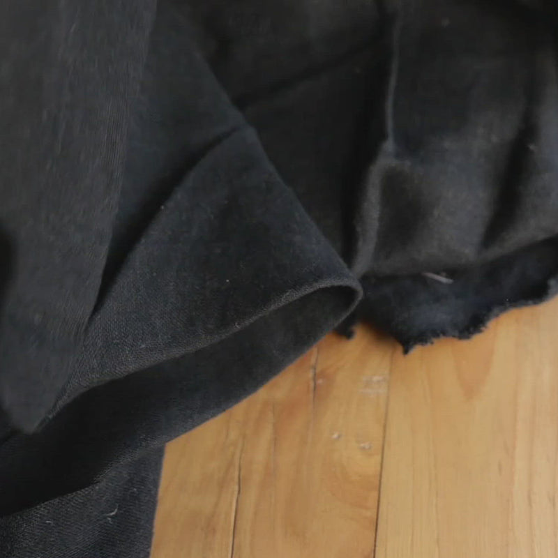 Hand crumples brushed linen in black.