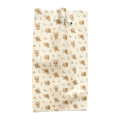 Cream fabric printed with a small brown flower. 