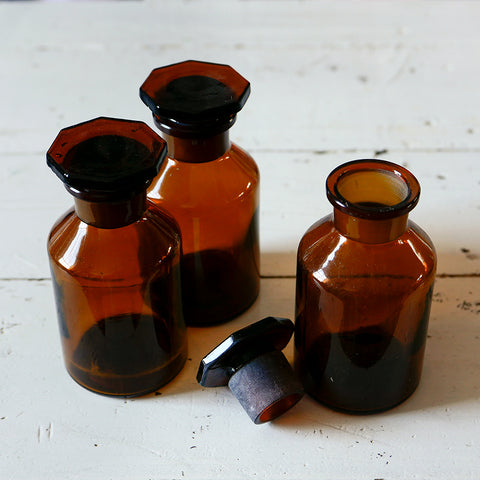 Three amber coloured glass bottles with octagonal shaped stoppers.