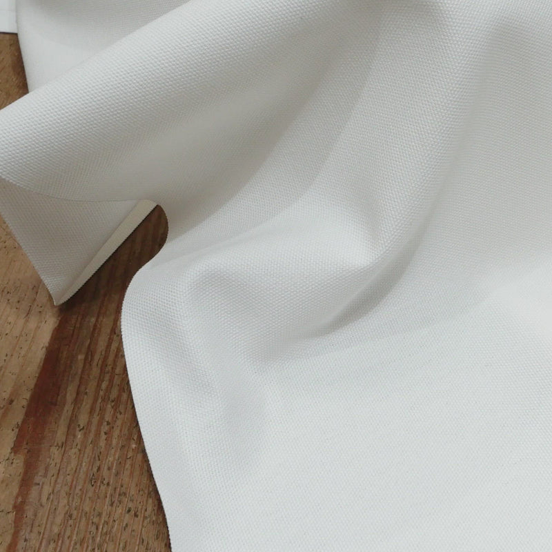 Hand crumples stiff white canvas.