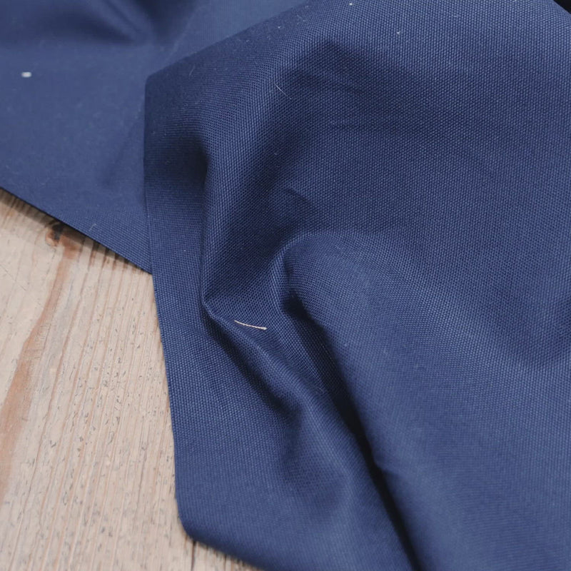 Hand crumples stiff navy canvas. 