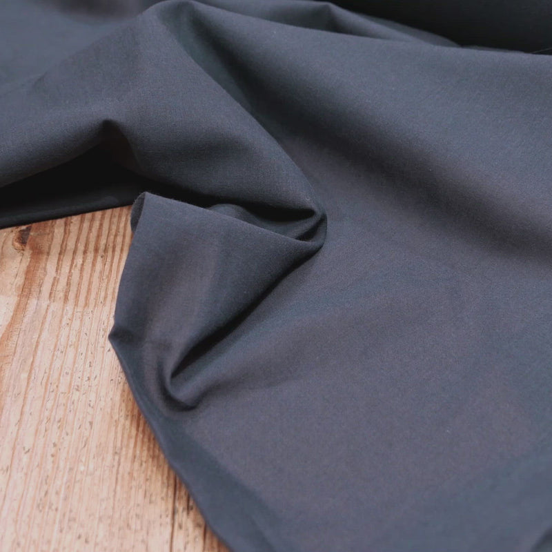Hand crumples slightly sheer navy fabric.