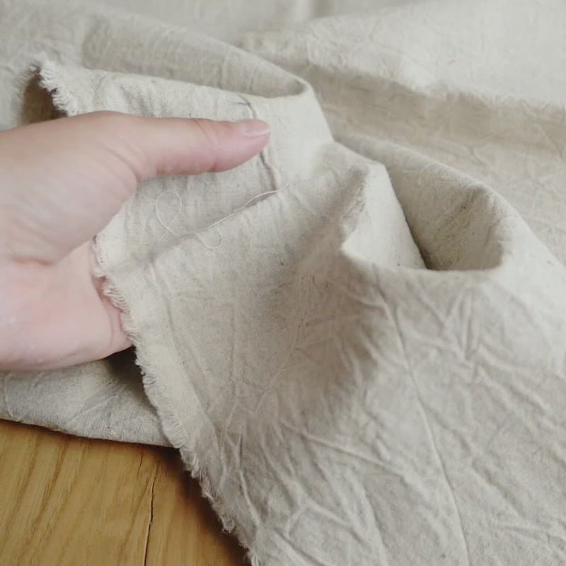 Plain cream fabric with a creased texture. 