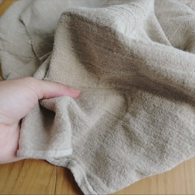 Natural undyed fabric with a washed and crumpled texture.