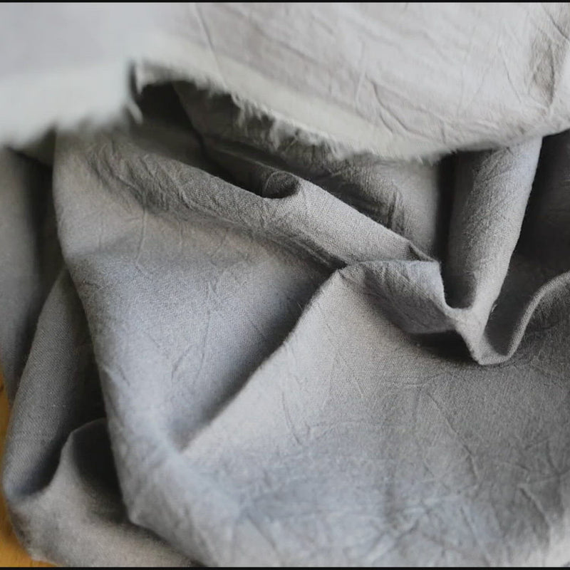 Plain grey fabric with a creased texture. 